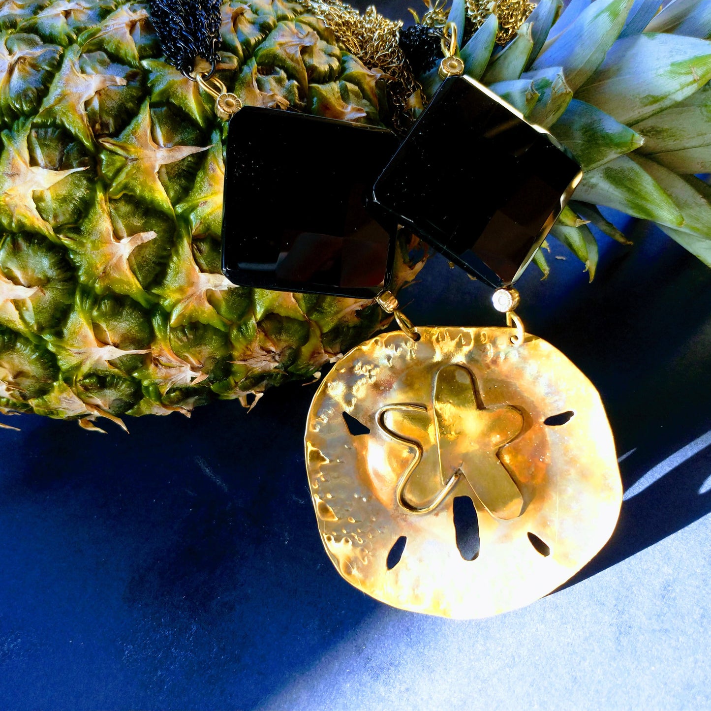 Close-up shot of sand dollar pendant with large black onyx beads.