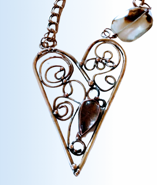 Close-up shot of a filigree pendant in copper with a bezel set smokey quartz. 