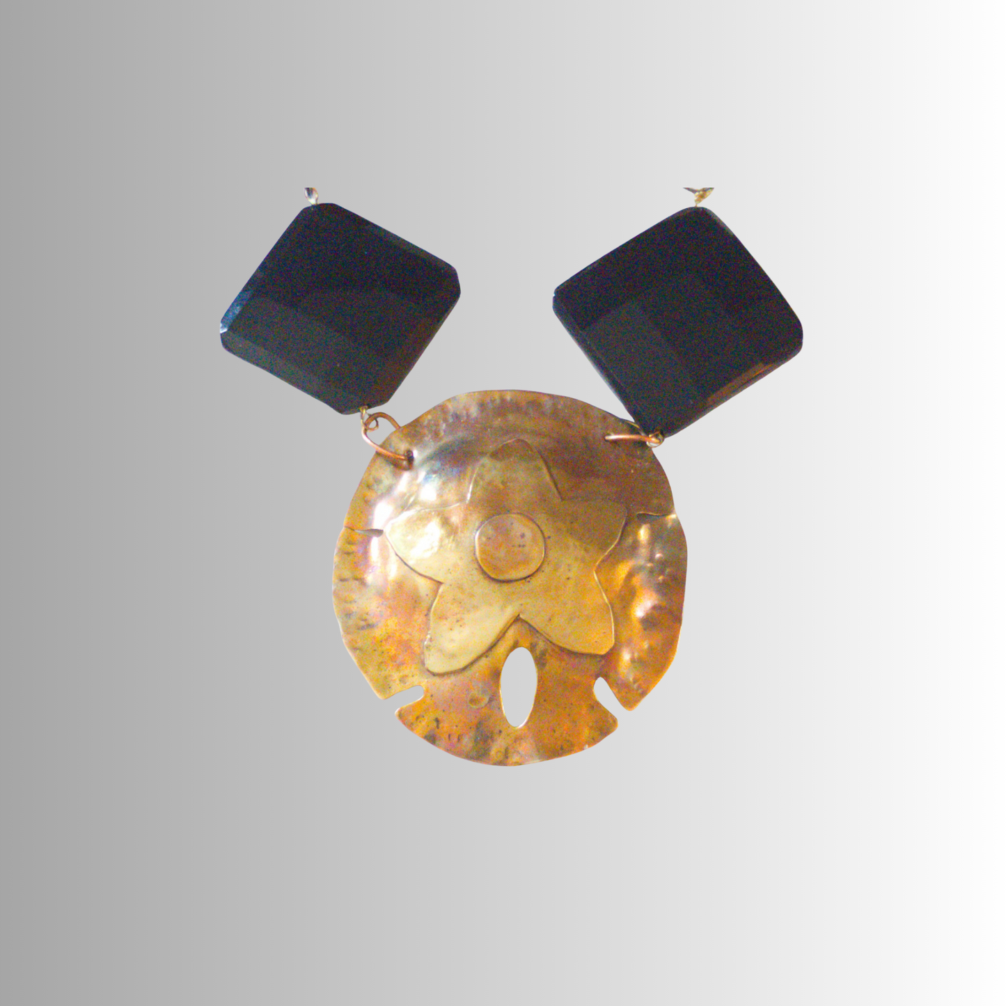 Close-up of five-star sand dollar pendant in brass on gray background.